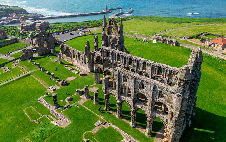 Church ruins on a coastal headland, surrounded by grass, viewed from above, with the sea in the background.