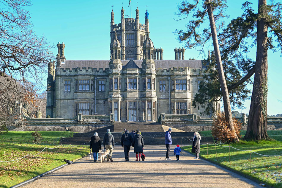 A group of people of different ages walking up a path towards a castle-style building