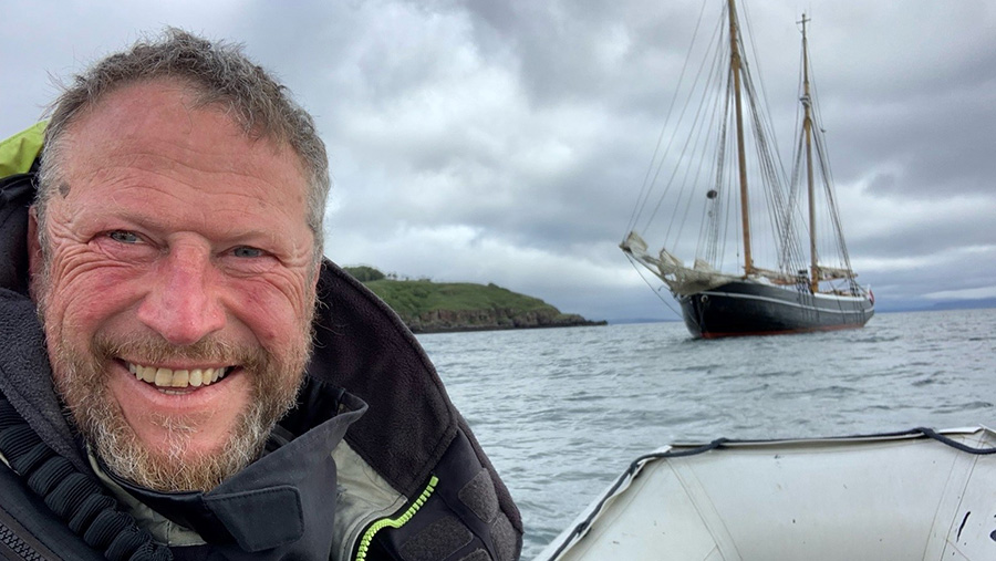 Person smiling at camera with boat in the background