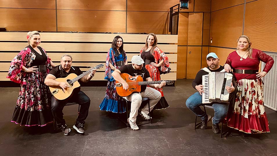 three musicians with guitars and accordions and four women dancers wearing traditional eastern European dress