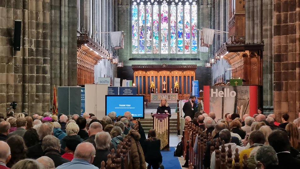 A person gives a speech inside a large church to a crowd of people seated in pews