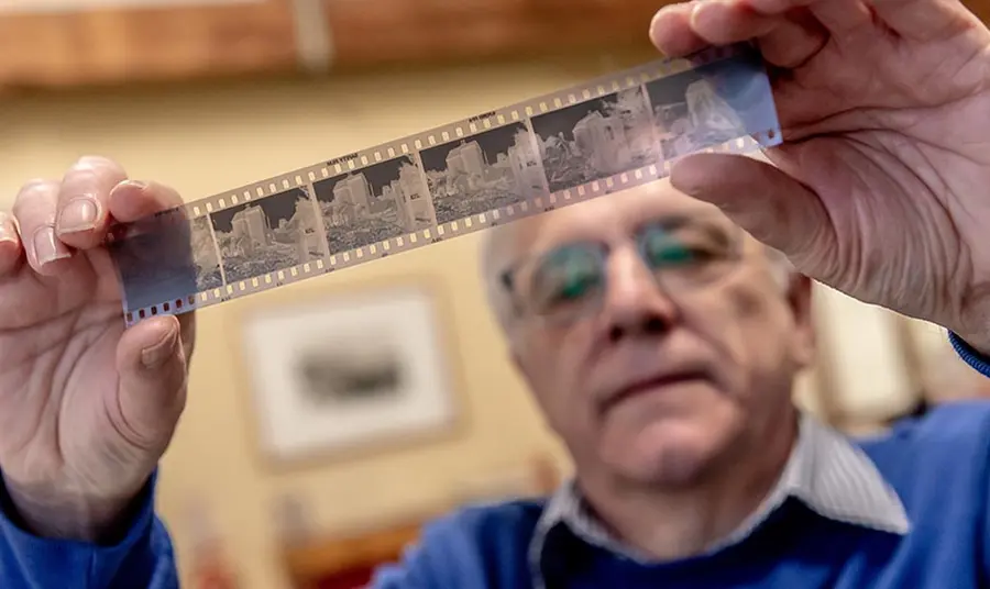 a man holds up a strip of photographic negatives