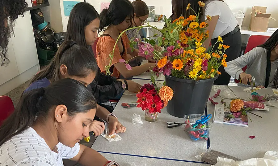 A group of people create artwork at a table covered in flowers