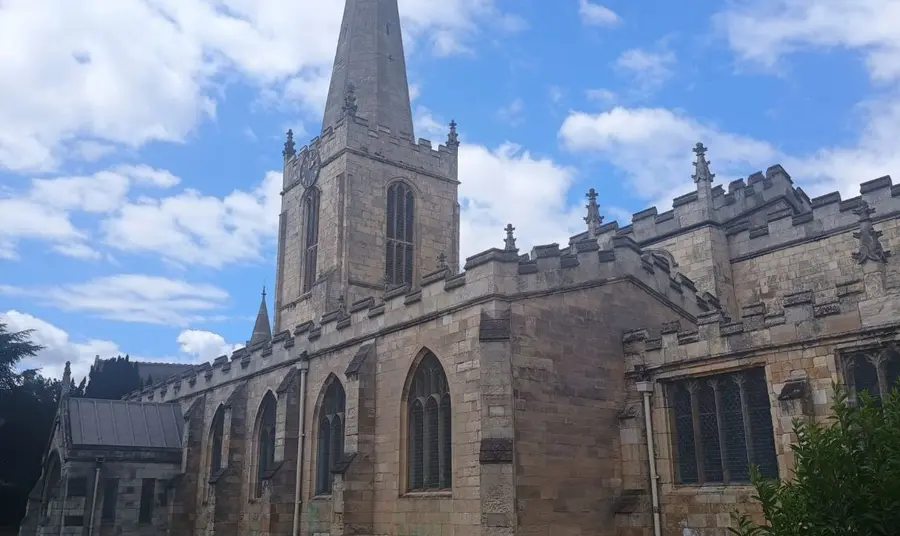 A village church with a tall with a hexagonal spire.