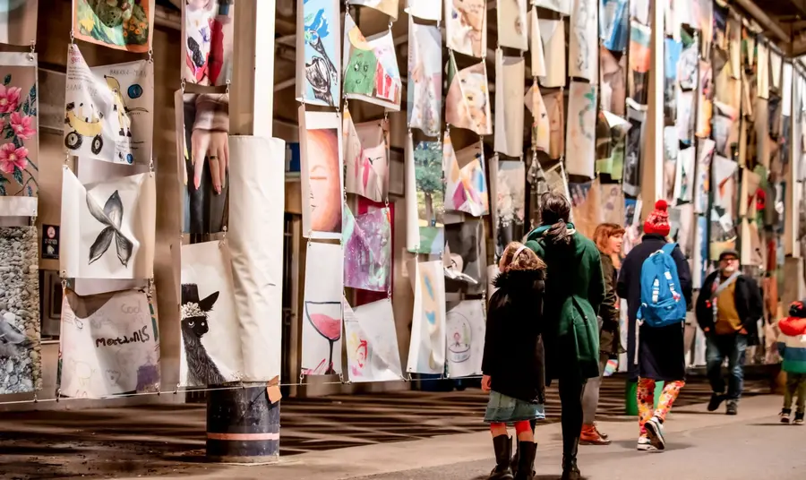 Artwork created by local people on display with a group of people studying them. 