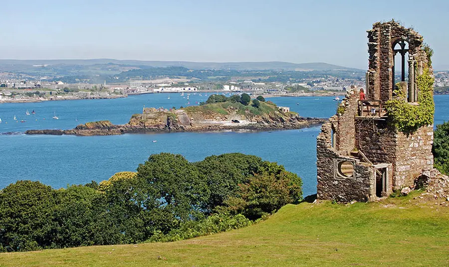 A ruined folly with a coastal landscape during summer in the background