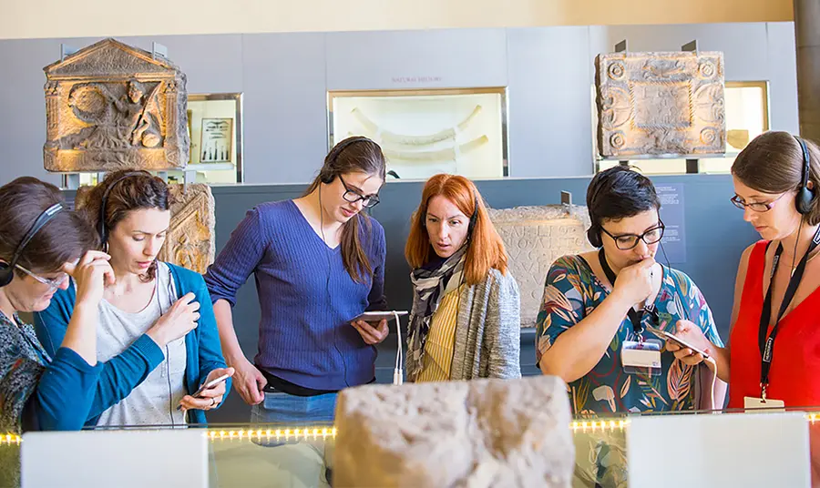 Six people using devices at a museum exhibition 