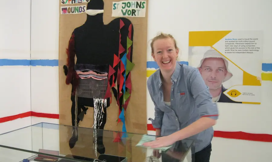 A person cleans a display cabinet in the Henshaws exhibition