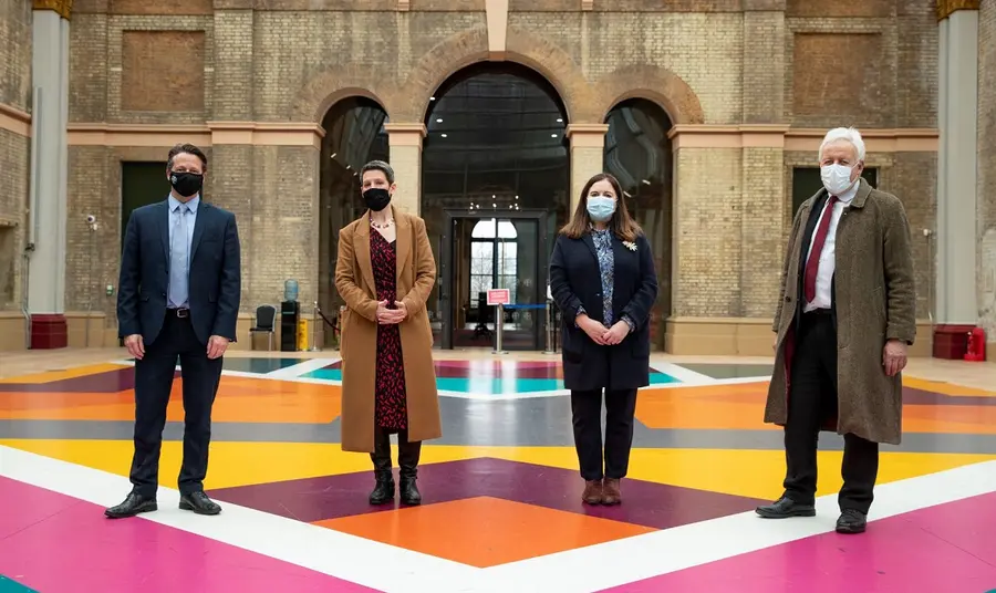 Four people standing inside Alexandra Palace, socially distanced with masks on