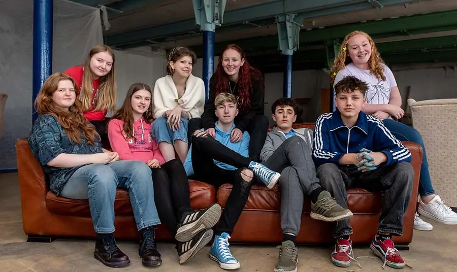 Young people gathered around a red sofa