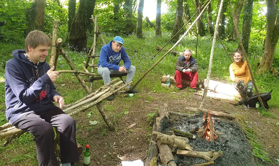 People chat round a campfire in woodland