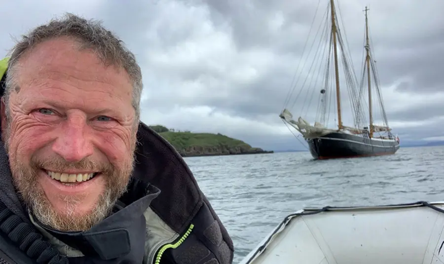 Person smiling at camera with boat in the background