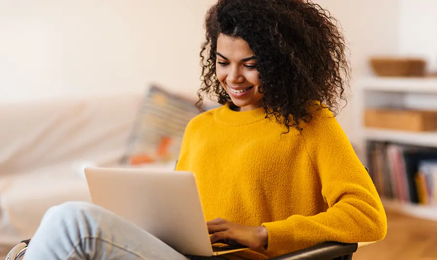 Young woman smiling as she looks at a laptop screen