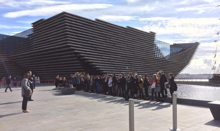 A group of people standing outside the V&A Dundee building