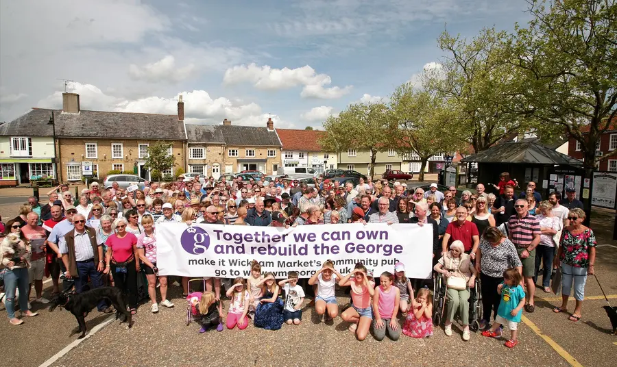 Wickham Market community holding up a banner to save The George pub.