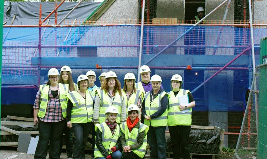 A group of people stand in front of the building during its restoration