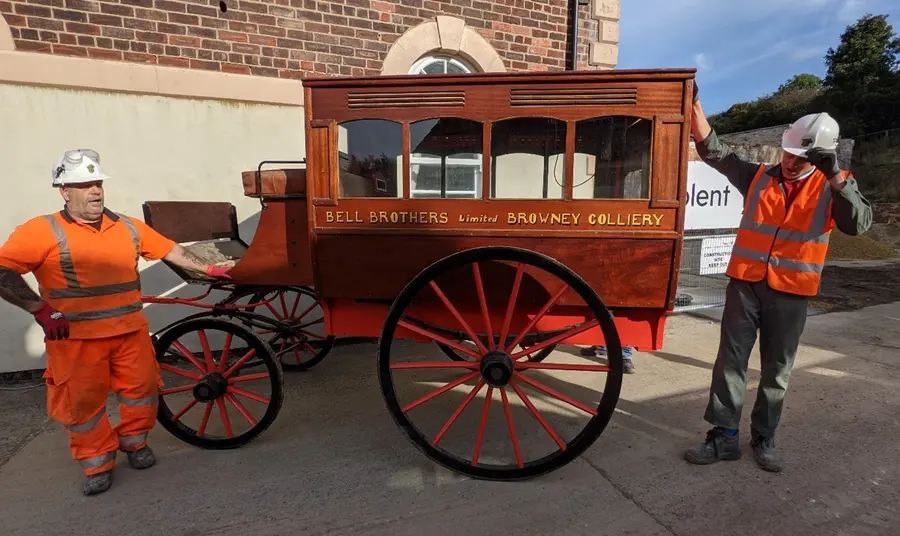 Two workmen standing either side of the horse-drawn ambulance