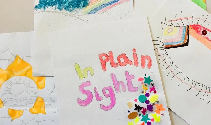 Colourful handmade poster for the In Plain Sight project. Rainbows, flowers and an eye decorated with LGBTQ+ colours can be seen