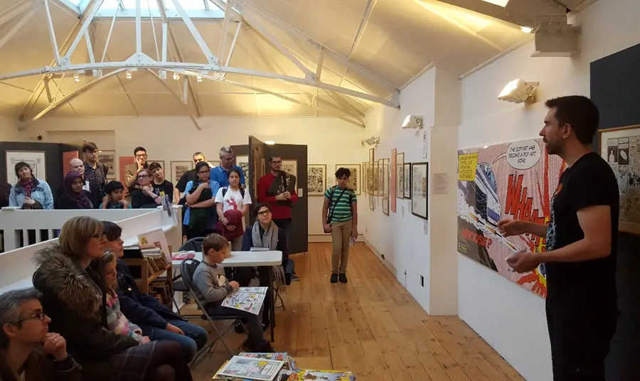 A comic Creator giving a talk in front of a crowd at The Cartoon Museum