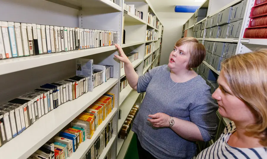 Two people looking at tapes on shelves