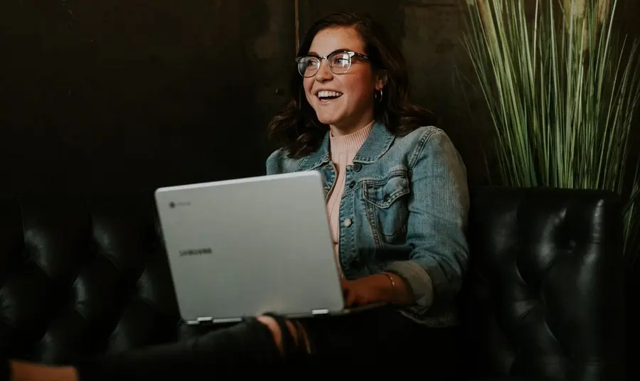 Person using laptop whilst smiling