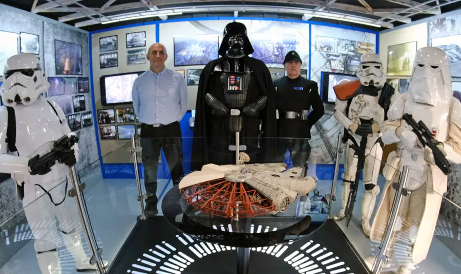 Storm Troopers and Darth Vader standing around a model of the Millennium Falcon