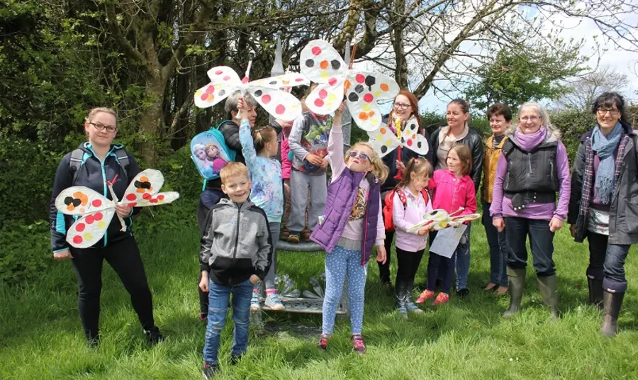 Group of volunteers and children in a park waving paper butterflies