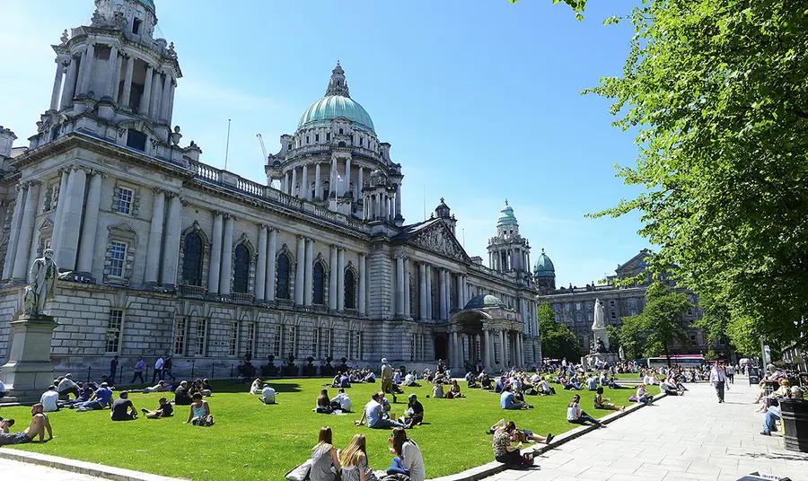 People sitting on grass in front of large building