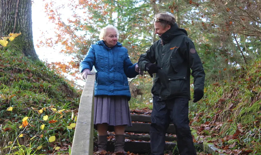 A man helping a woman down stairs in a forest