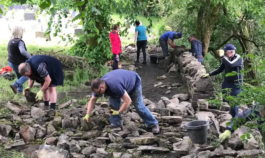 Volunteers work on rebuilding dry stone walls at St Nicholas Church, 