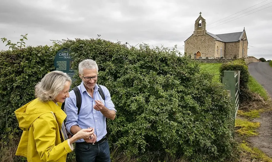 Two people standing with a church on a hill in the background