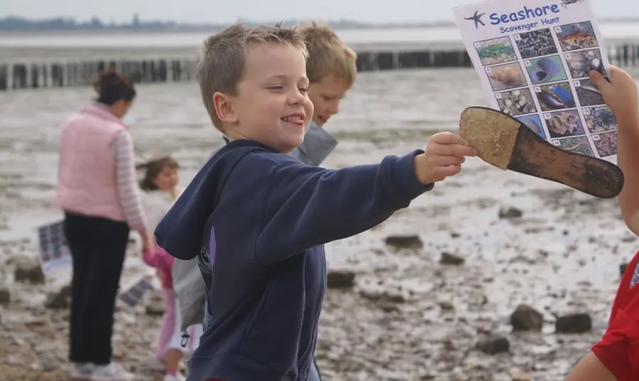 Child playing on a beach with families attending a beach scavenger hunt