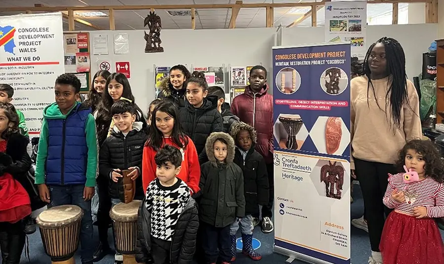 A group of children posing for a photograph, some holding family objects