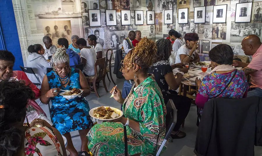 Groups of older people sitting eating at tables at the Migration Museum