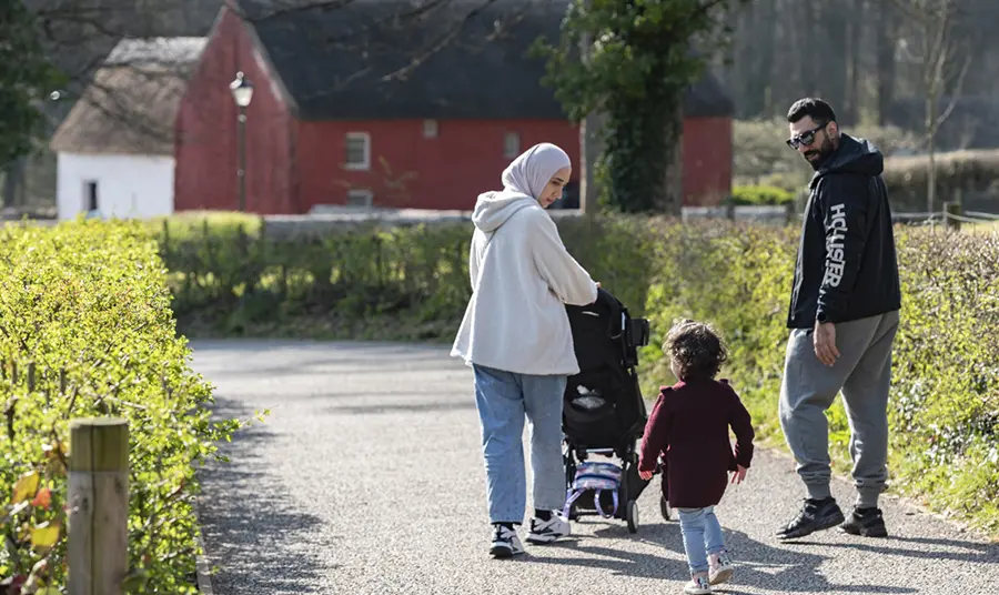 A family of two adults and a young child in the grounds of St Fagans Museum