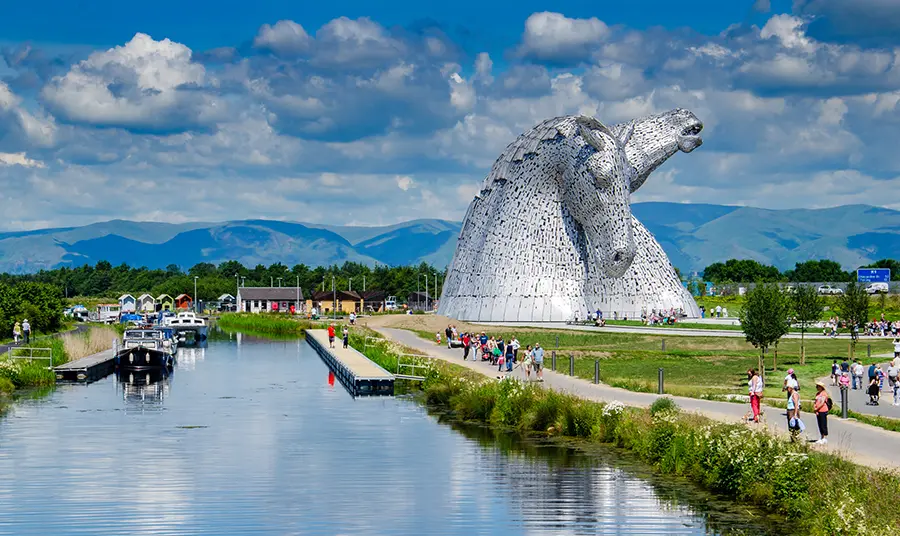 The Falkirk Kelpie sculptures, with boats on the canal and people walking along the paths