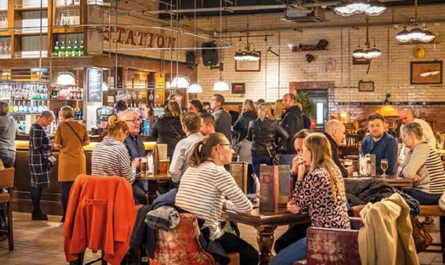 A well lit, crowded bar with people sitting at tables