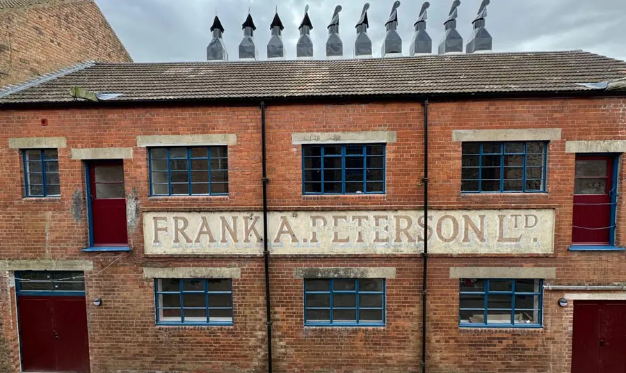 A front of a red brick building with many chimneys on top of the fish smokehouse 