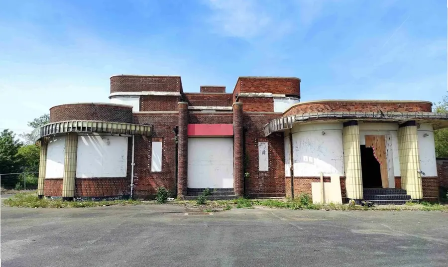 The art deco red brick structure of the Iron Duke, with its windows boarded up and with visible damage to the facade.