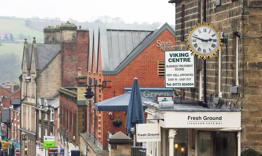 Brick buildings, signs, shopfronts and people on a main street in Belper