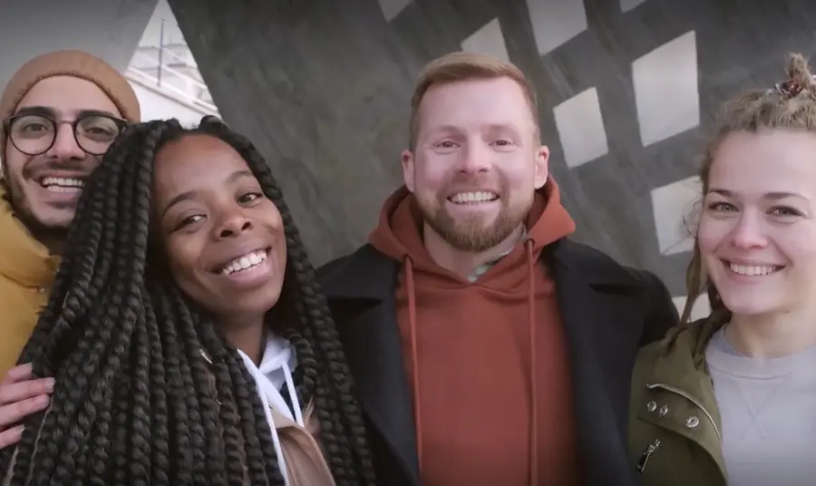 Four people standing together with big smiles on their faces