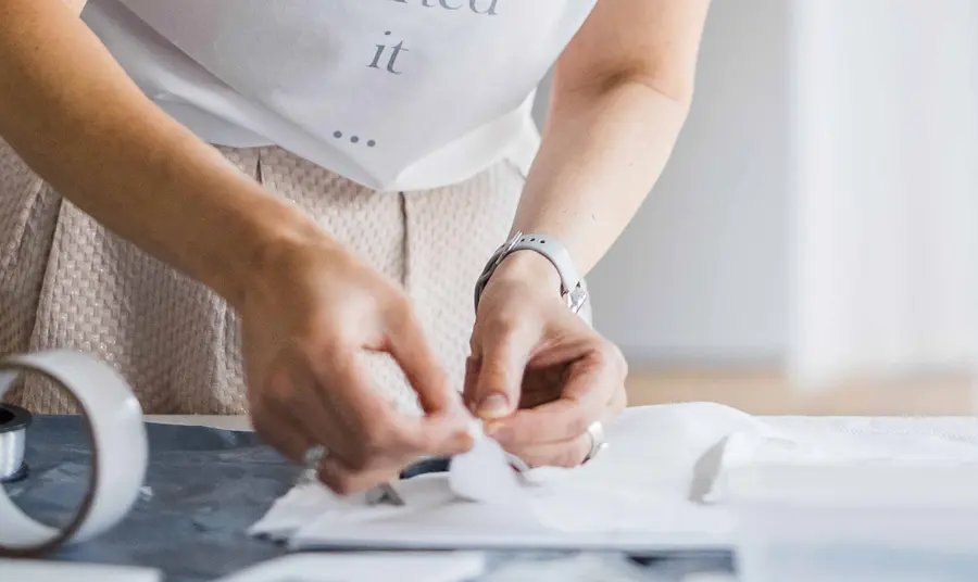 A person's hands handling a folded piece of white linen on a flat surface