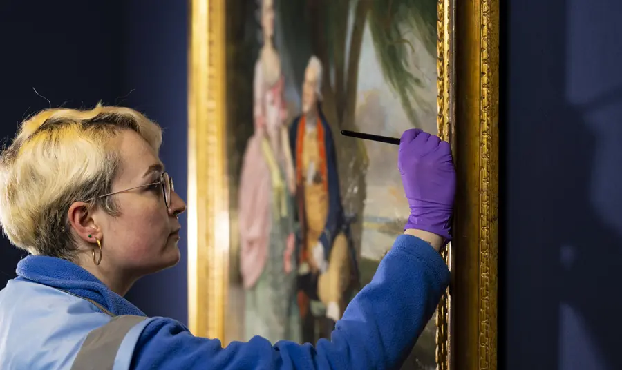 A close up of a person conserving a painting on display in the National Portrait Gallery