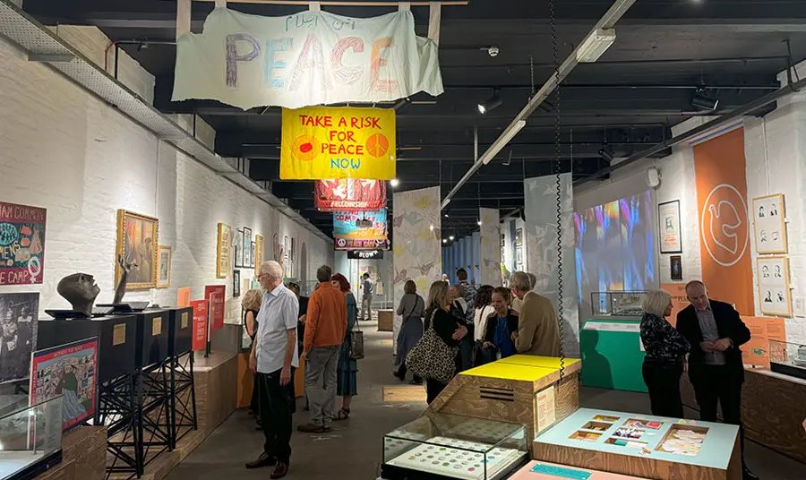 People walk around the exhibits including peace banners and posters