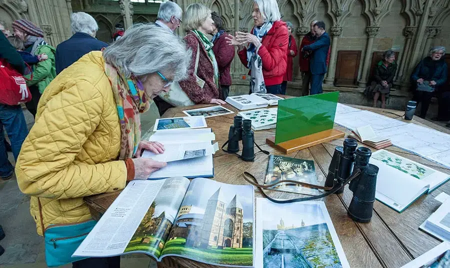 An older woman looks at magazines and leaflets on a table in a busy church