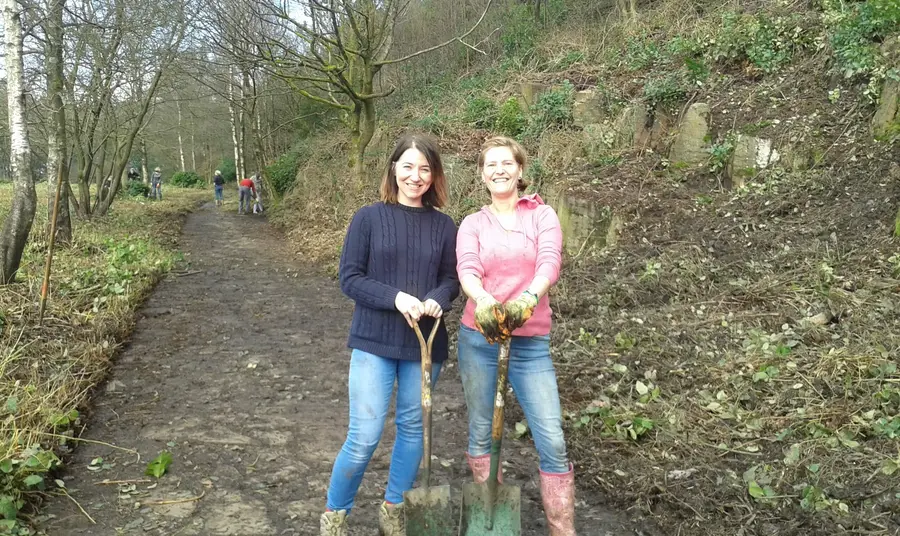 Two volunteers using shovels to help clear a footpath