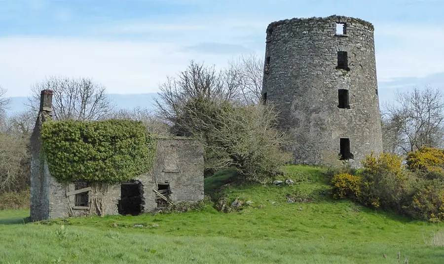a ruined stone windmill building in the countryside