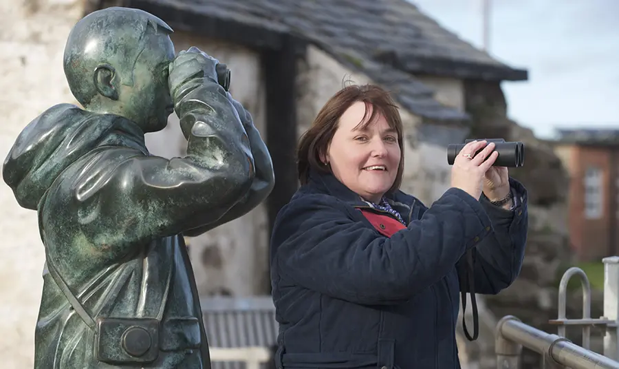 Woman with binoculars next to statue