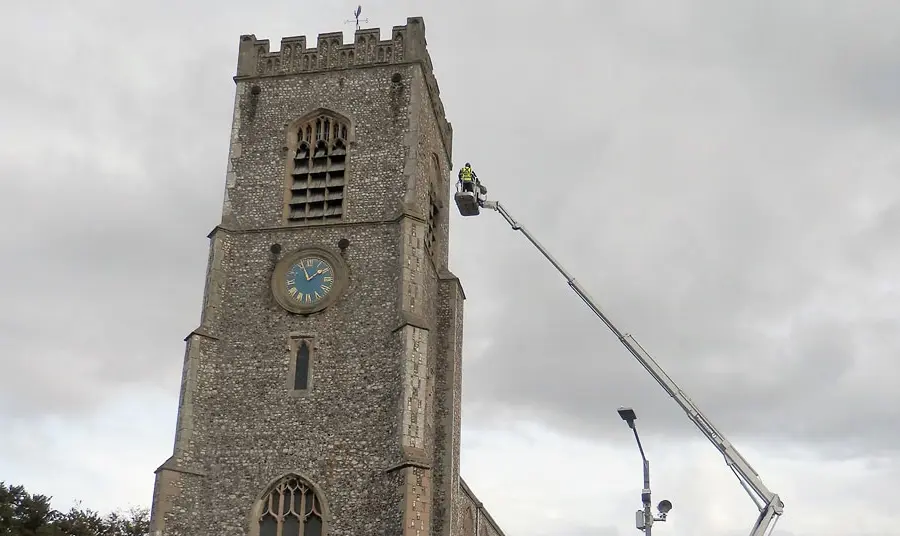 The tower of St Nicholas with a person on a crane assessing the tower roof