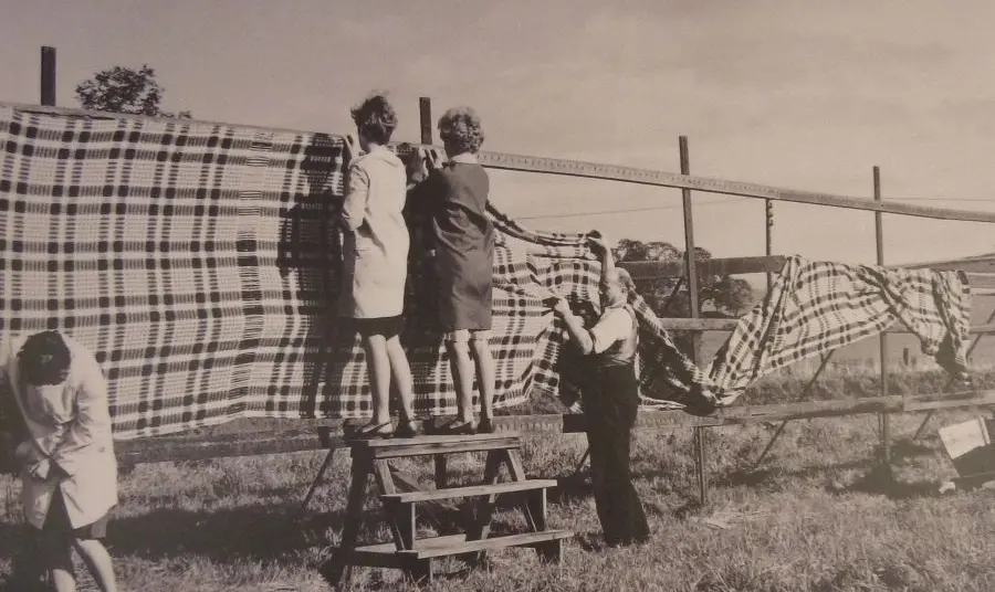 An archive image of people hanging cloth on tenter frames